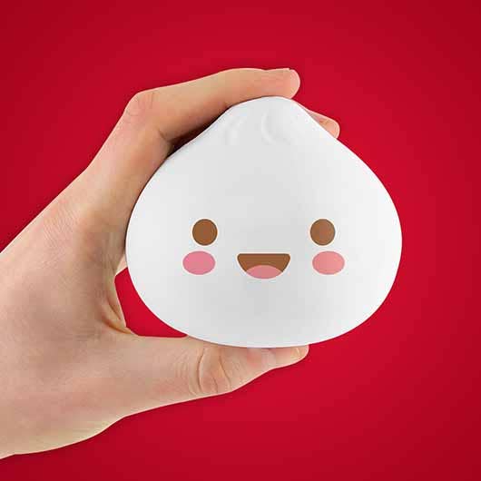 A hand holds a Dumpling Stress Toy designed to provide calming relief.