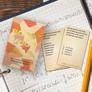  A tabletop scene featuring a game, a notebook, pencils, and a book arranged neatly.