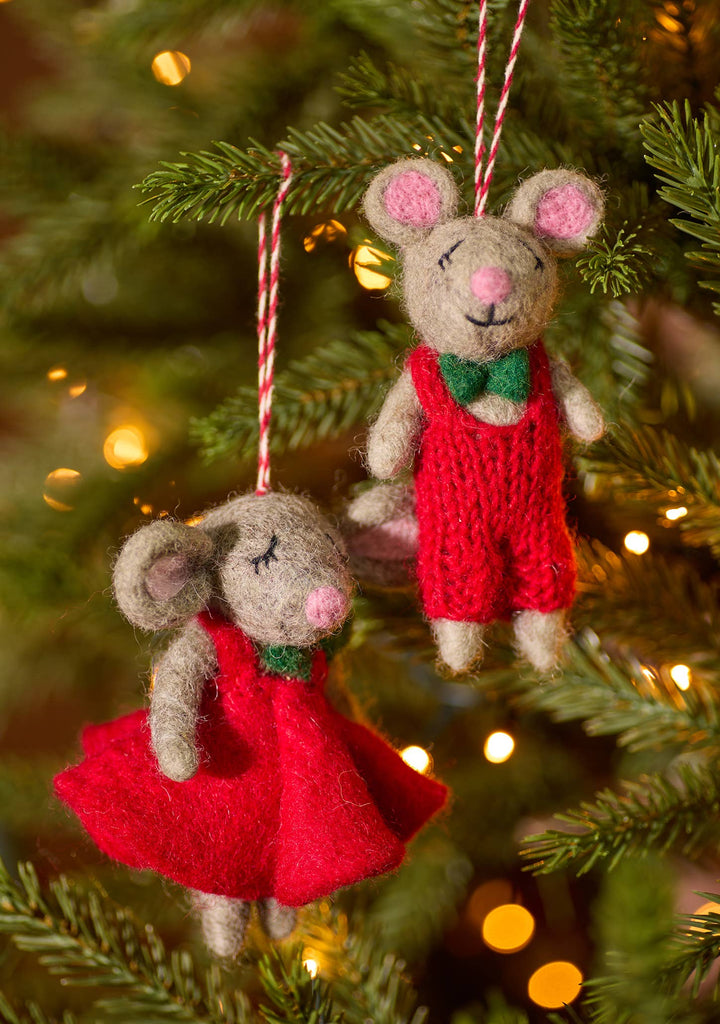Two small mice in red dress and other in red dungarees playfully hang from a decorated Christmas tree, adding a festive touch to the scene.