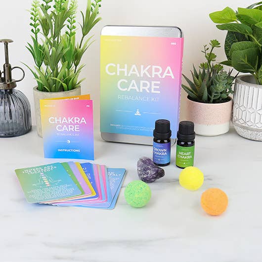 A chakra care kit containing: 20 chakra care cards, 3  bath bombs, 2 essential oils, and an Amethyst crystal, aimed at enhancing energy flow and emotional well-being.