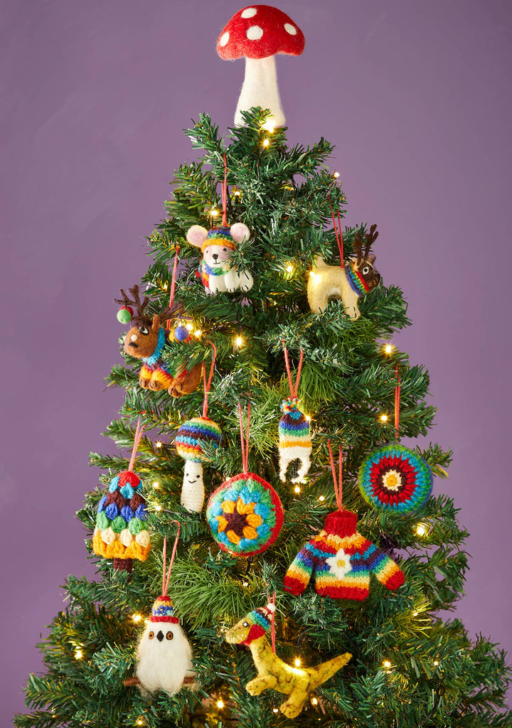 A beautifully decorated Christmas tree featuring a charming knitted ornament atop its branches.