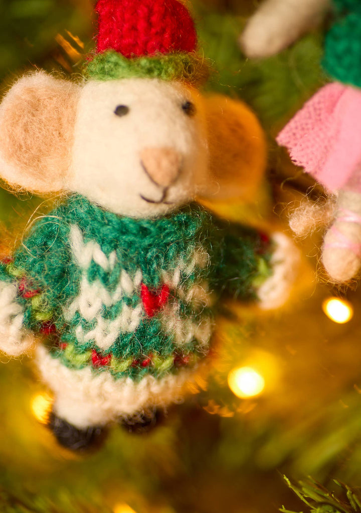 A small mouse in a cozy sweater and hat perched on a festive Christmas tree, adding a whimsical touch to the holiday decor.