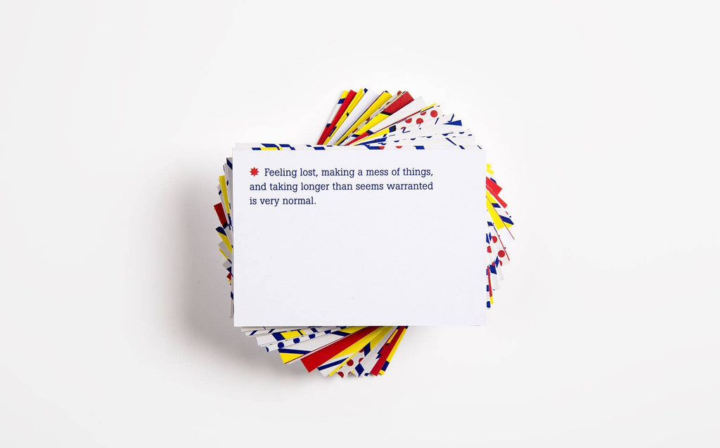 A quote-filled note card lies on a bright white surface on top of other brightly coloured Confidence cards, highlighting its thoughtful message.
