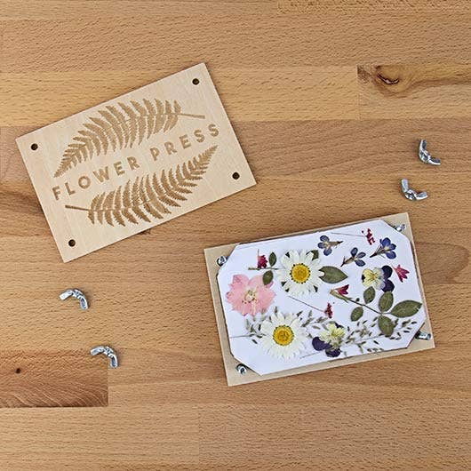 A DIY box featuring a flower press and a card, symbolizing creativity and the beauty of pressed flowers.