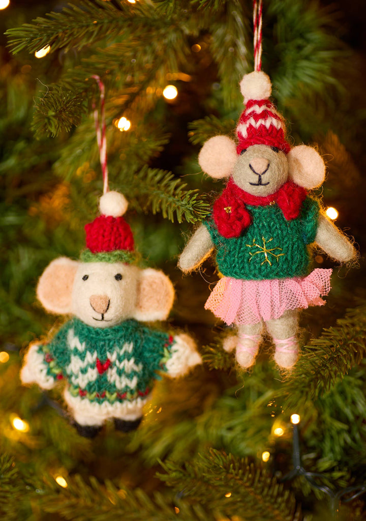 Two small Christmas ornaments with red and white threads hang from a tree, featuring festive hats and jumpers for a joyful touch.