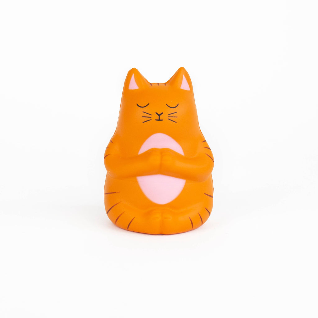 A small orange cat toy with closed eyes, resting peacefully on a white surface