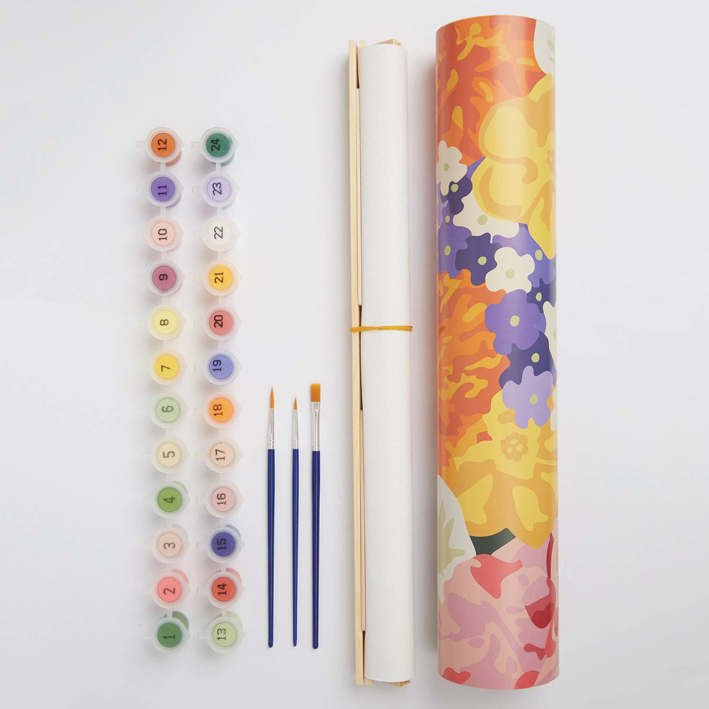 A roll of blank paper with paint tubes and brushes, suggesting preparation for a creative painting session.