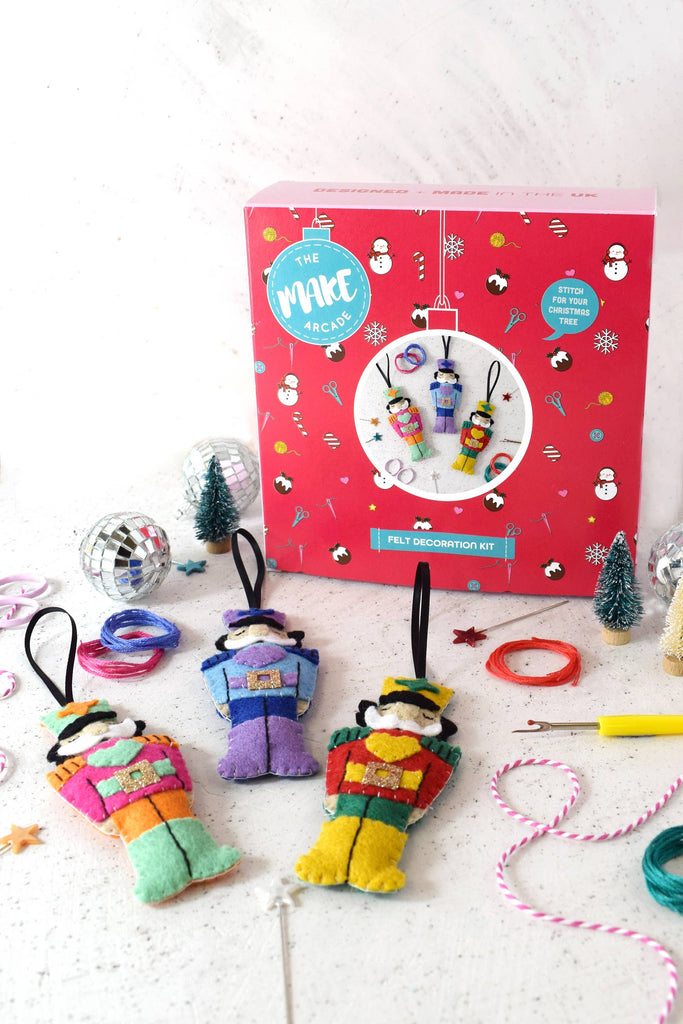 A box filled with colourful felt ornaments arranged around a beautifully decorated Christmas tree