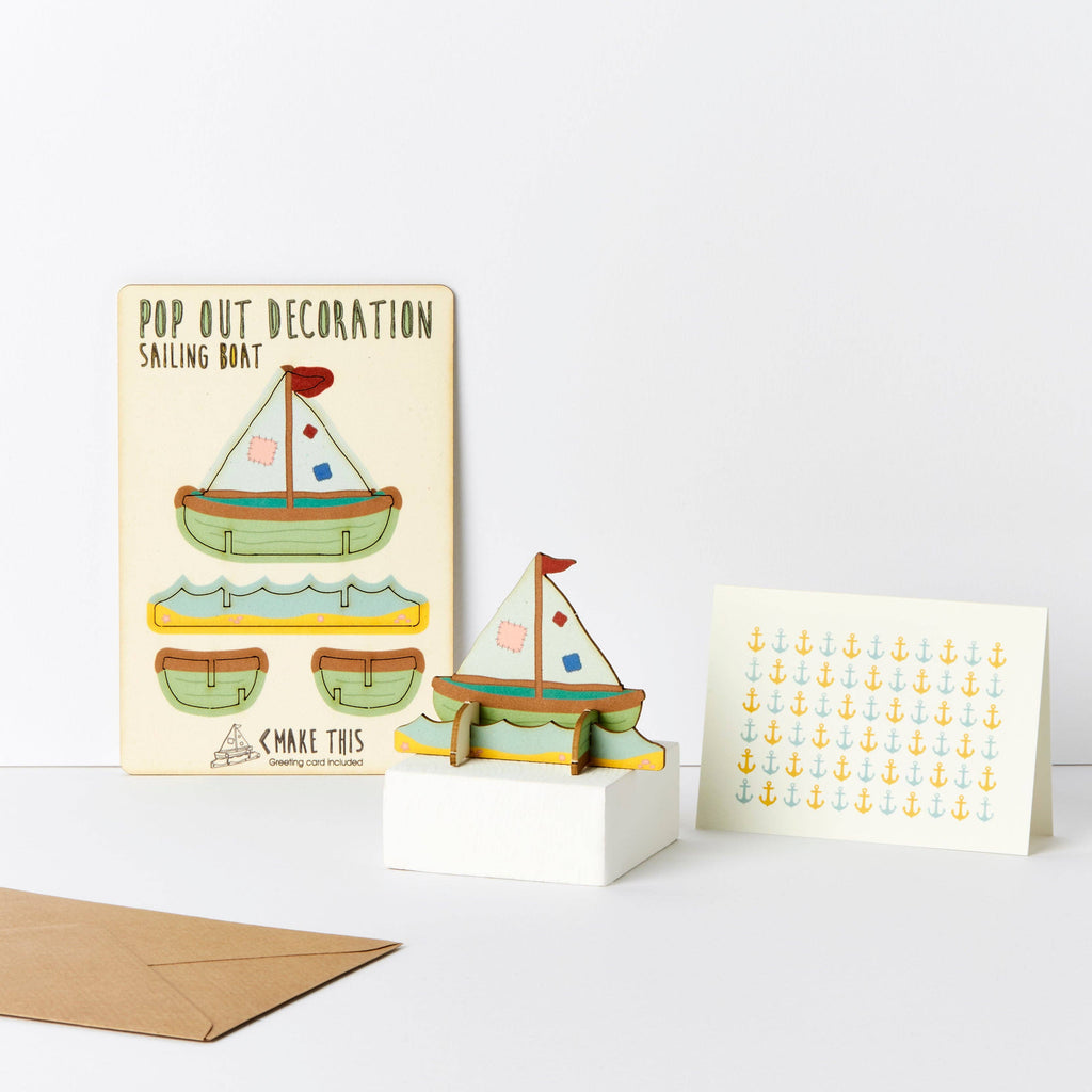 Sailing Boat with green hull and white patchwork sails wooden greeting card on beach and waves standing base