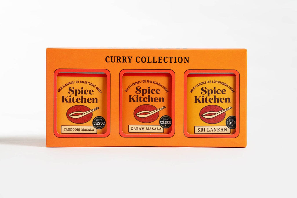 An assortment of curry spices arranged in a spice kitchen, featuring colourful jars and labels for each spice.