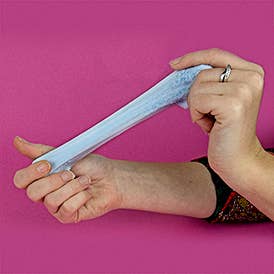 A person is stretching Therapy Putty holding it in both hands on a purple backdrop.