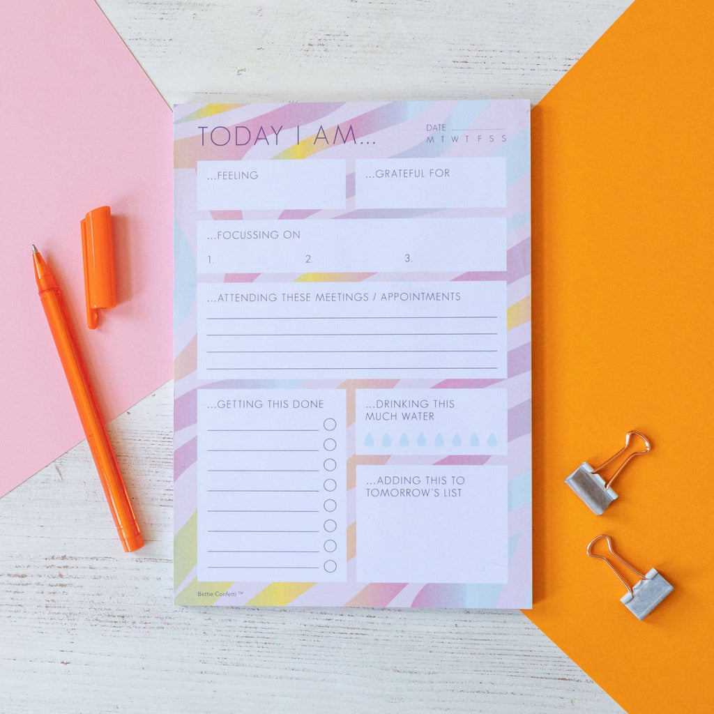 A bright coloured notepad with an orange pen placed on top, ready for writing notes or ideas.