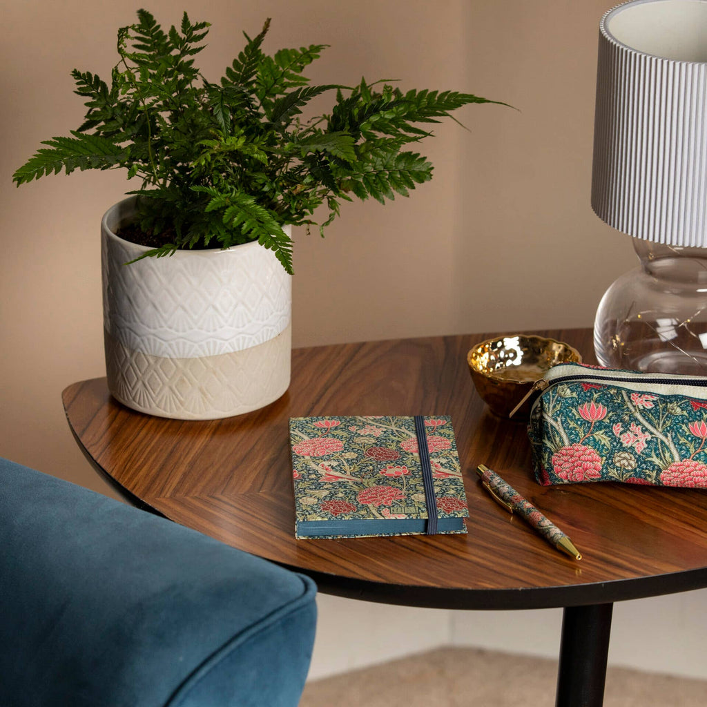 William Morris notebook on a coffee table with a pen, captured in a lifestyle photography shot, showcasing a cosy home setting.